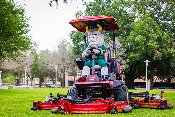Rocky D. Bull rides an industrial mower on the Tampa campus.