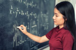 woman writing equation on chalkboard