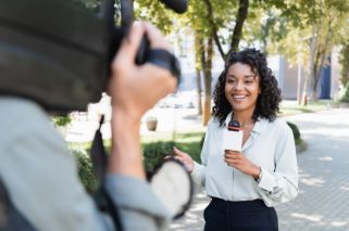 smiling woman with microphone standing in front of film crew