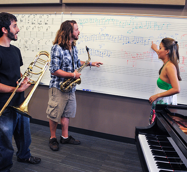 Music students discussing components of a melody in a rehearsal classroom.