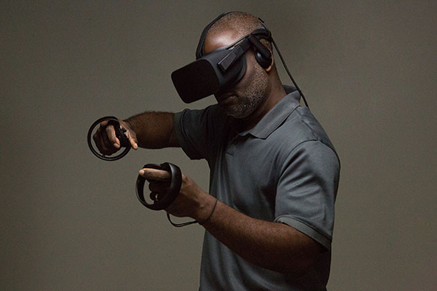 McArthur Freeman wears virtual reality gear with arms raised as he sculpts with virtual reality technology