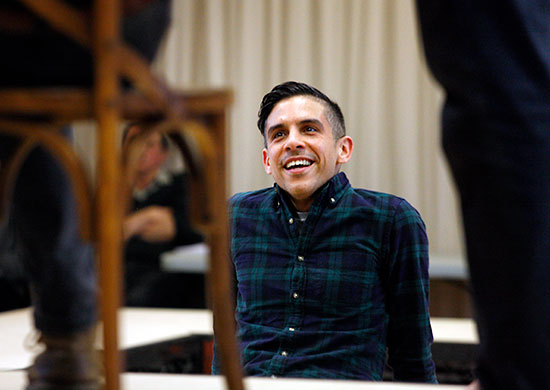 Matthew Lopez looks toward foreground performers on stage while attending a rehearsal for The Inheritance