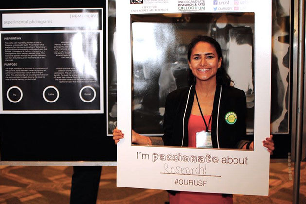 Catherine Gomez holds up large instant photo frame prop at the 2017 USF Undergraduate Research and Arts Colloqium
