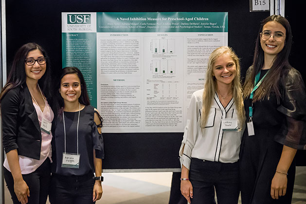 Daisy Solis, Adriana Melgan, Lindsay Power, and Carla Formoso Pico pose for a photo in front of their research poster titled "A Novel Inhibition Measure for Preschool Children” at the 2018 USF Undergraduate Research Symposium 