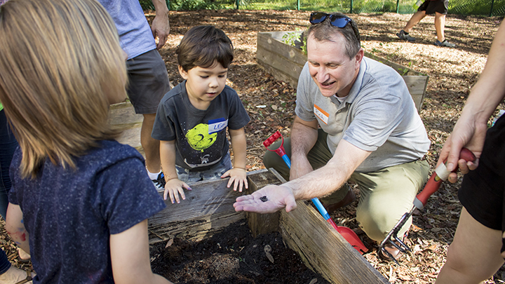 Dean Robert Knoeppel works with preschool students while preparing soil for a community garden