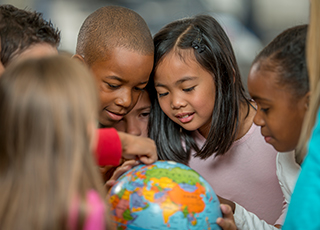 Young children gathered around a globe