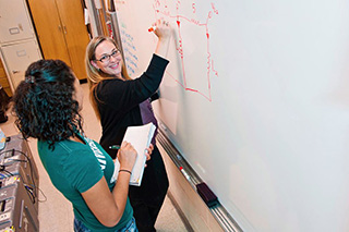 Student and Professor Studying Math at Whiteboard in Classroom