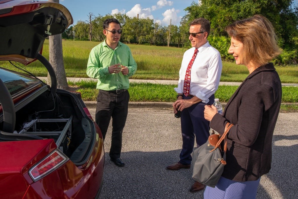 Li (left) gives a technical overview of his lab’s test vehicle to Bertini (middle) and to U.S. Department of Transportation Deputy Assistant Secretary Diana Furchtgott-Roth (right) during the USF tech demo.