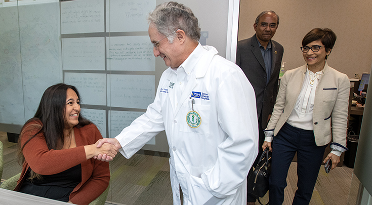 Natasha Ram is surprised by Dr. Charles Lockwood, Dr. Lynette Menezes and Dr. Gopal Thinakaran entering a conference room and shakes Dr. Lockwood's hand.