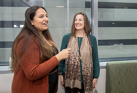 Natasha Ram and Dr. Kira Zwygart share a laugh in a conference room near windows.. 