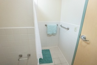Shower with curtain up and towel racks on the wall.