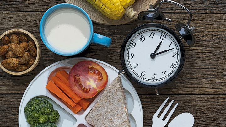 Picture of food with a clock laying on a table