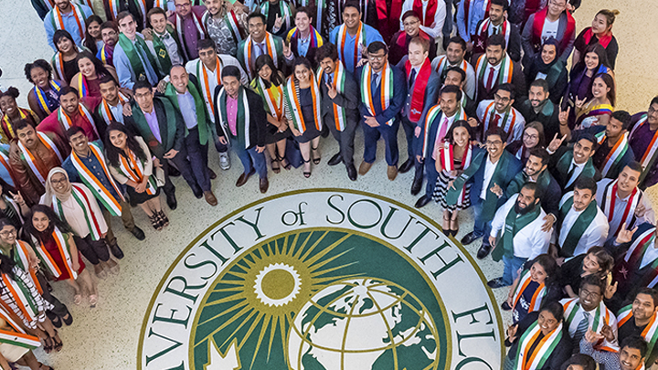 A picture of a group of international students standing around the usf logo.