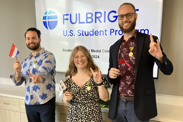 Three Fulbright recipients holding flags