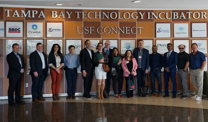 group shot of the Canada-Florida Chamber of Commerce with representatives from USF standing in front of the USF Technology Incubator CONNECT wall