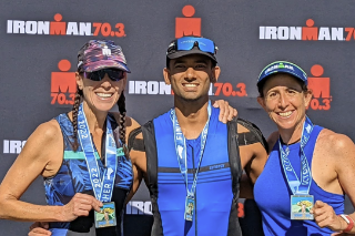 Aditya Sharma is pictured in the middle of 3 conteztants proudly displaying their Ironman tiriathalon medals