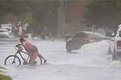 Anne Langhorne struggles with her bike while crossing the flooded street on Shore Acres Boulevard NE near 40th Avenue NE in St. Petersburg on Oct. 12, 2023. “This is the worst it's been the eight years I've lived here,” Langhorne said of the flooding. [ DIRK SHADD | Times ]