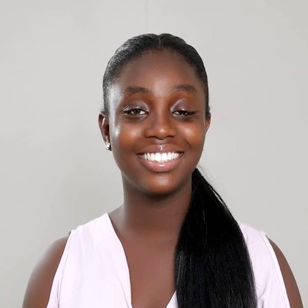 A woman with long dark hair smiles wearing a pink blouse