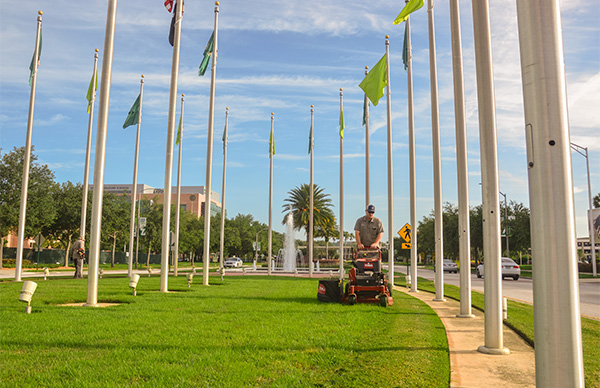A grounds employee mows the grass around the collins park.