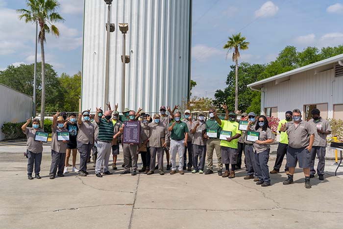 A large group of grounds employees pose for a photo after winning an award from the Vice President.