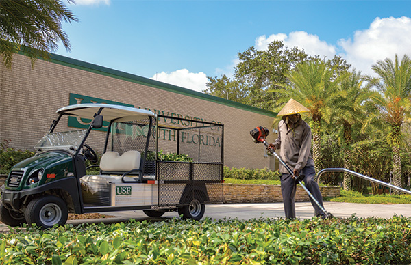 A grounds employee trims shrubs outside the SVC building.