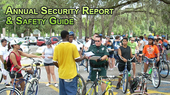 A USF police officer in a green uniform is handing out a report to a group of students with bicycles.
