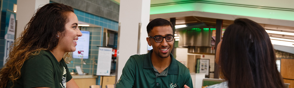 Three USF students sitting together at a dining hall.