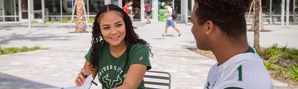 Two USF students sitting together on campus.