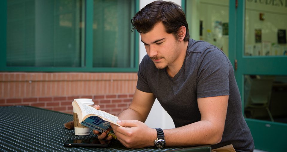 USF student sitting at a table reading a book.