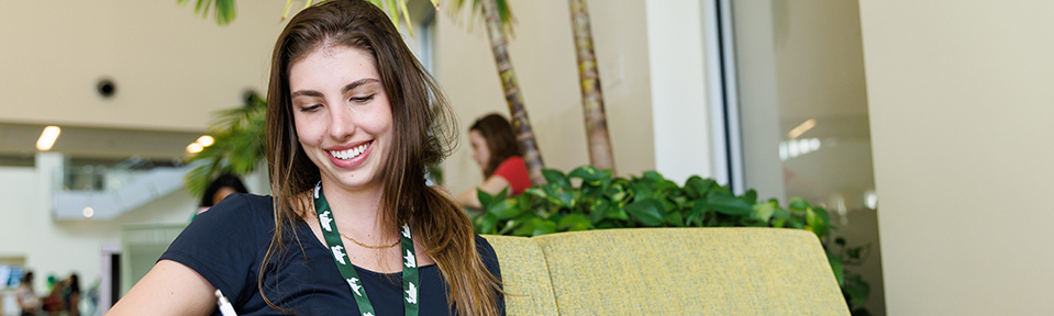 A USF student smiling and reading on her laptop.