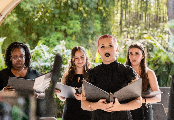 A group of women standing together in a choir and singing during a performance.
