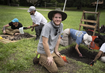 A group of students working outdoors digging and sorting through soil.