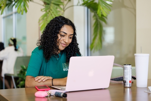 USF student using their laptop on campus, linking to the applicant portal.