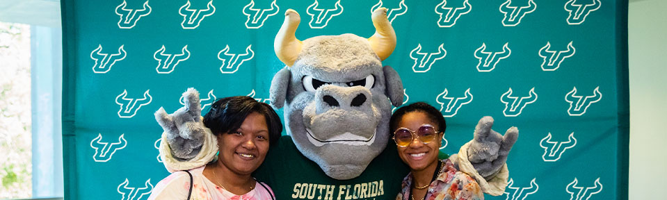 Two people posing for a picture with Rocky at a USF's Tampa campus event.