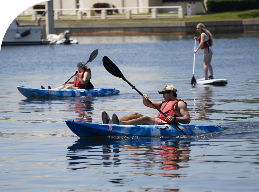 USF students kayaking and paddleboarding on the water.