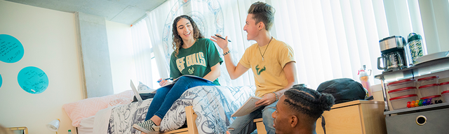 Three international USF students hanging out together in a dorm room.