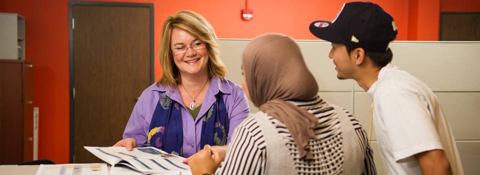 A student and his mother talking to a college counselor.