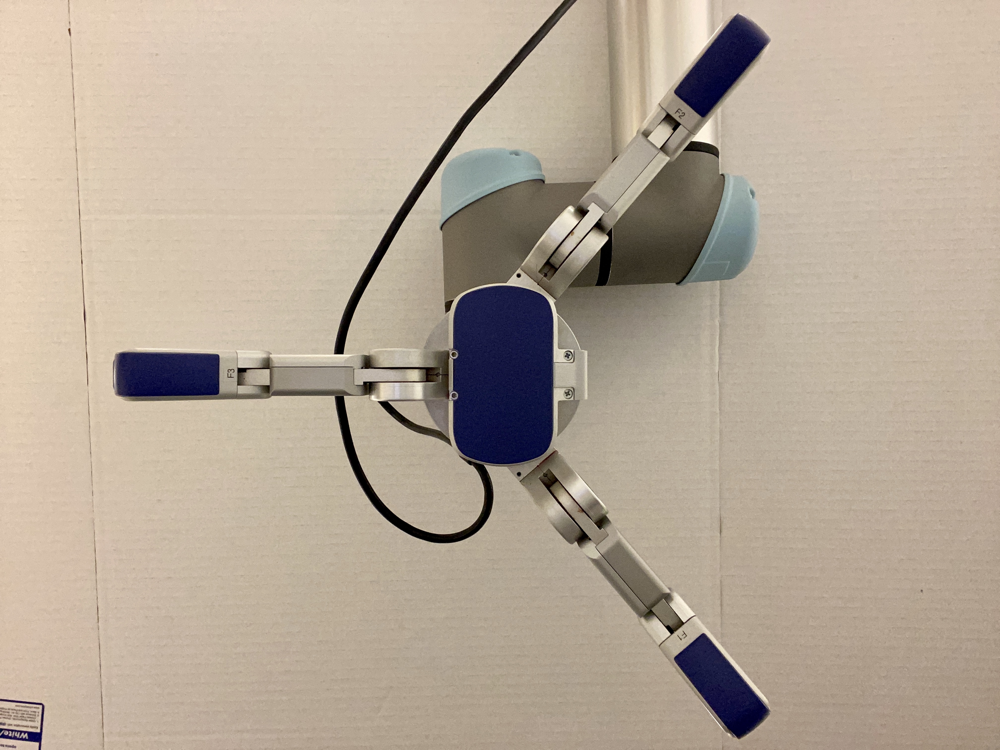 A robotic arm with three articulated segments and blue grippers is positioned against a plain white background, showcasing its mechanical design and functionalities. The arm appears ready for precise movements or tasks.