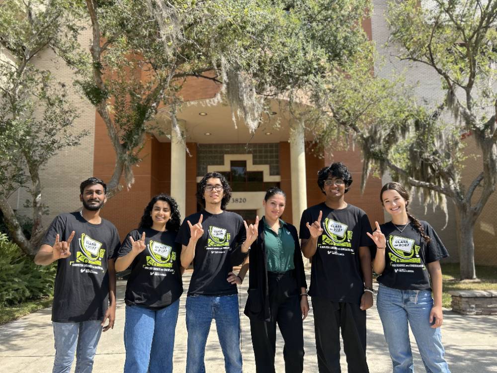 CSE Ambassadors holding up Bulls hand sign in front of a building