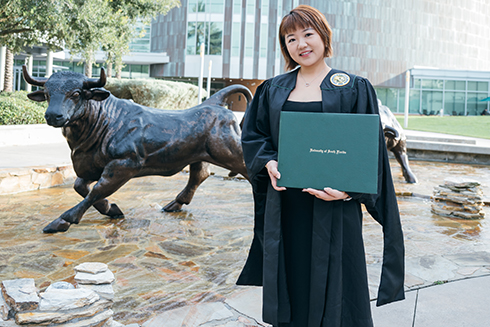 Xiangfei holding her degree outside the Marshall student center at USF
