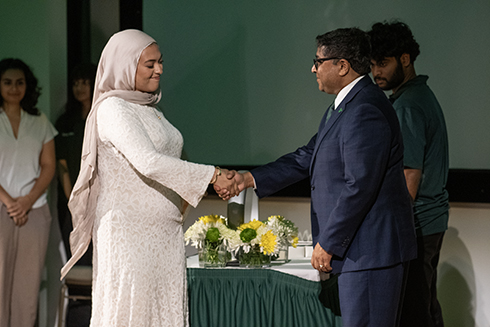 A student shakes the deans hand during the induction ceremony.