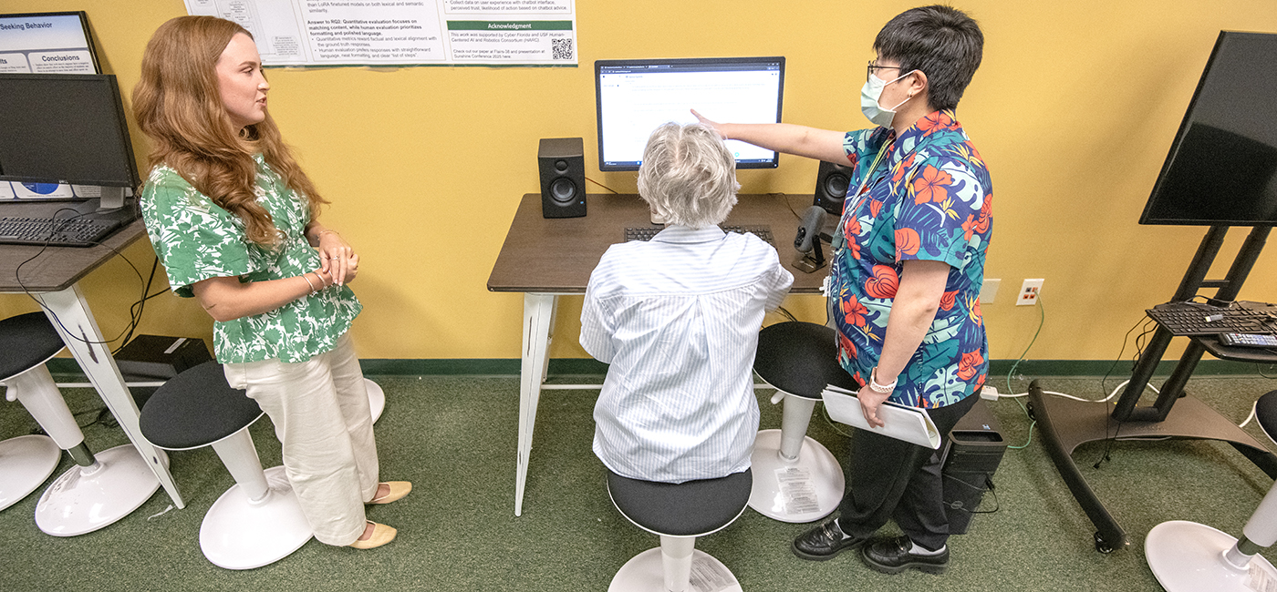 PHD student Marlena Bolton and USF assistant professor Ly Dinh describes how an AI system for seniors works to Jeanie Plyler.