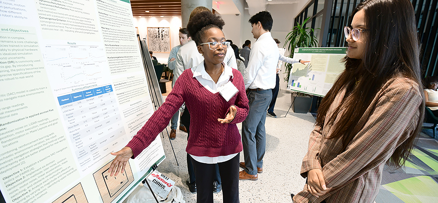 A student explains her research poster during the REU symposium.