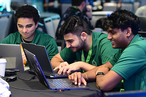 USF student Fagan Afandiyev, center, works with his CyberHerd team members at a competition.