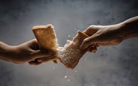 two hands tearing a piece of sliced bread in two