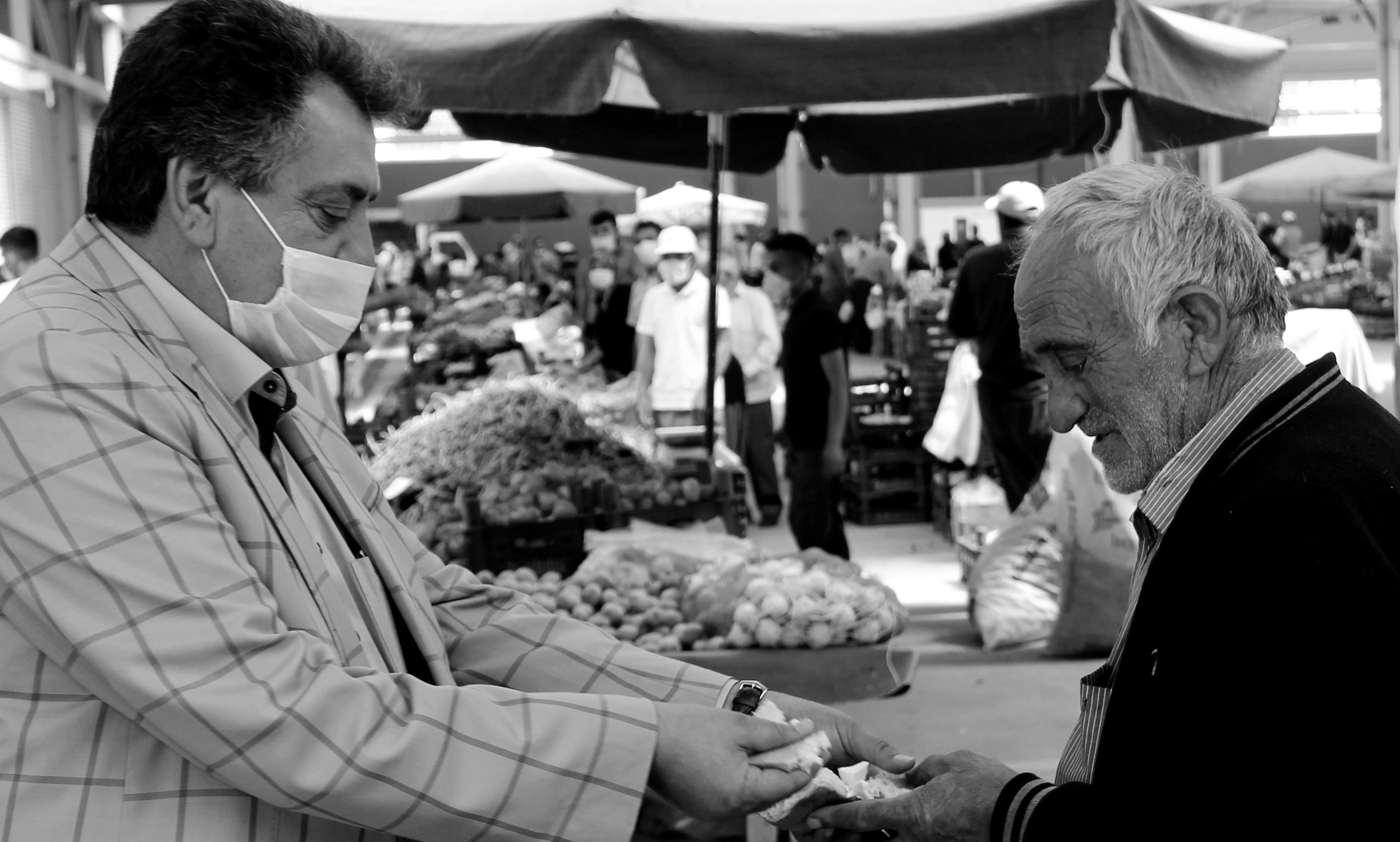 Man in mask and older man exchange food and money