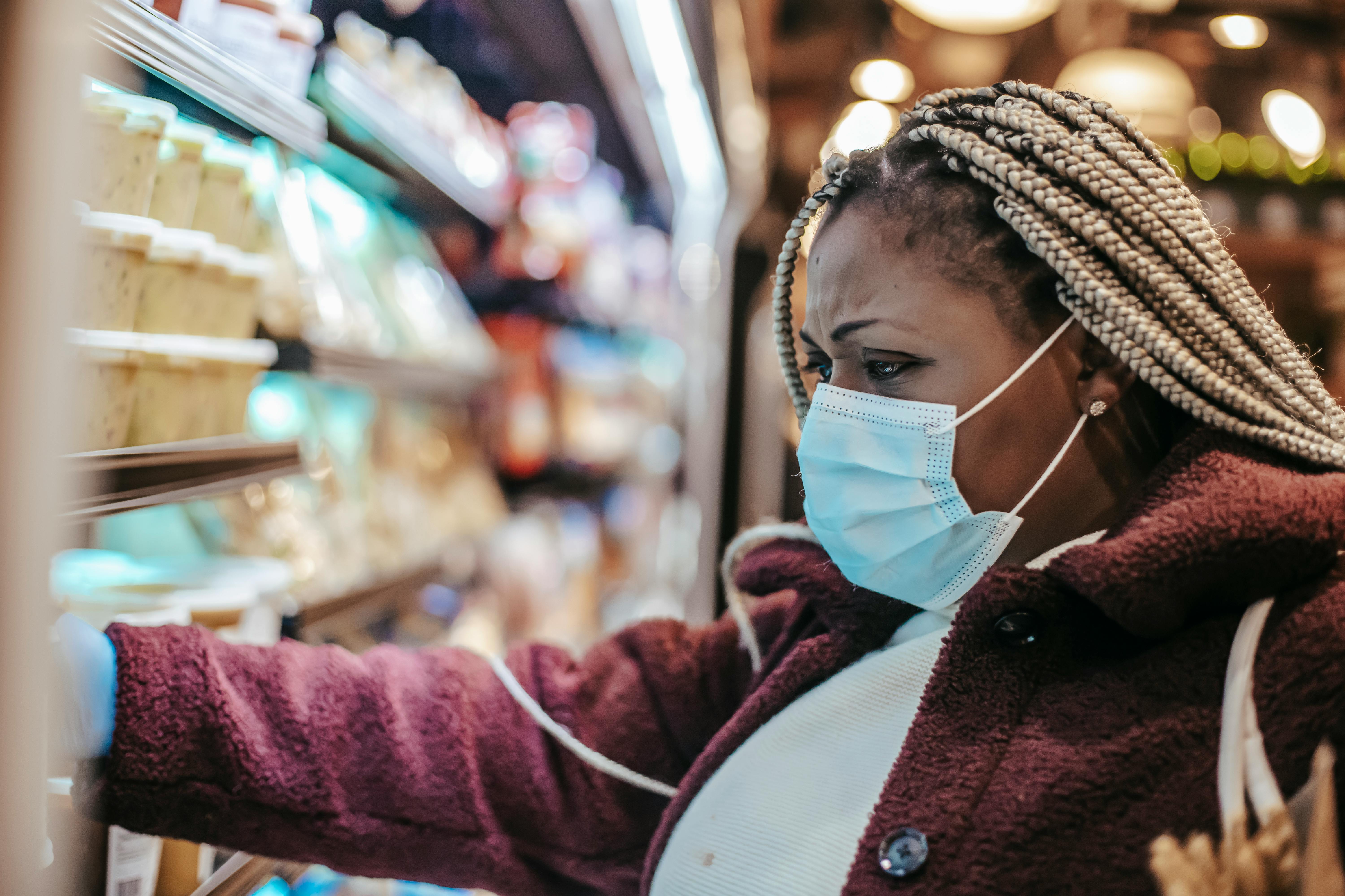 Women wearing a mask looks concerningly at food prices