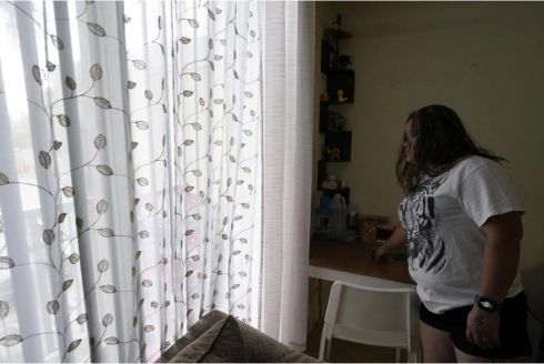 A mother of four looks out the window from her apartment, Aug. 24, 2023, in Homestead. The Honduran native worked as a house painter shortly after arriving in the U.S. in 2021.