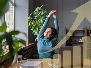 smiling woman seated at desk stretching arms overhead