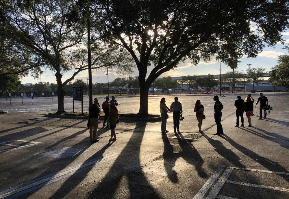 people standing in a parkling lot under a tree